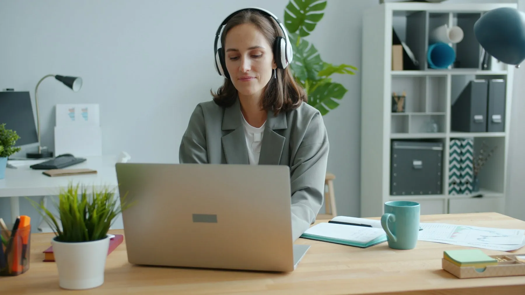 A woman on a video call at her laptop in a bright office.