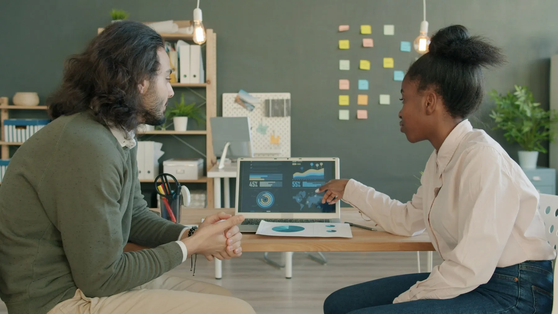 Two colleagues reviewing an analytics dashboard on a laptop.