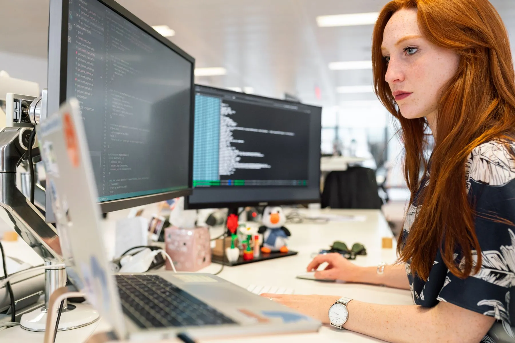 An engineer working at two monitors full of code.