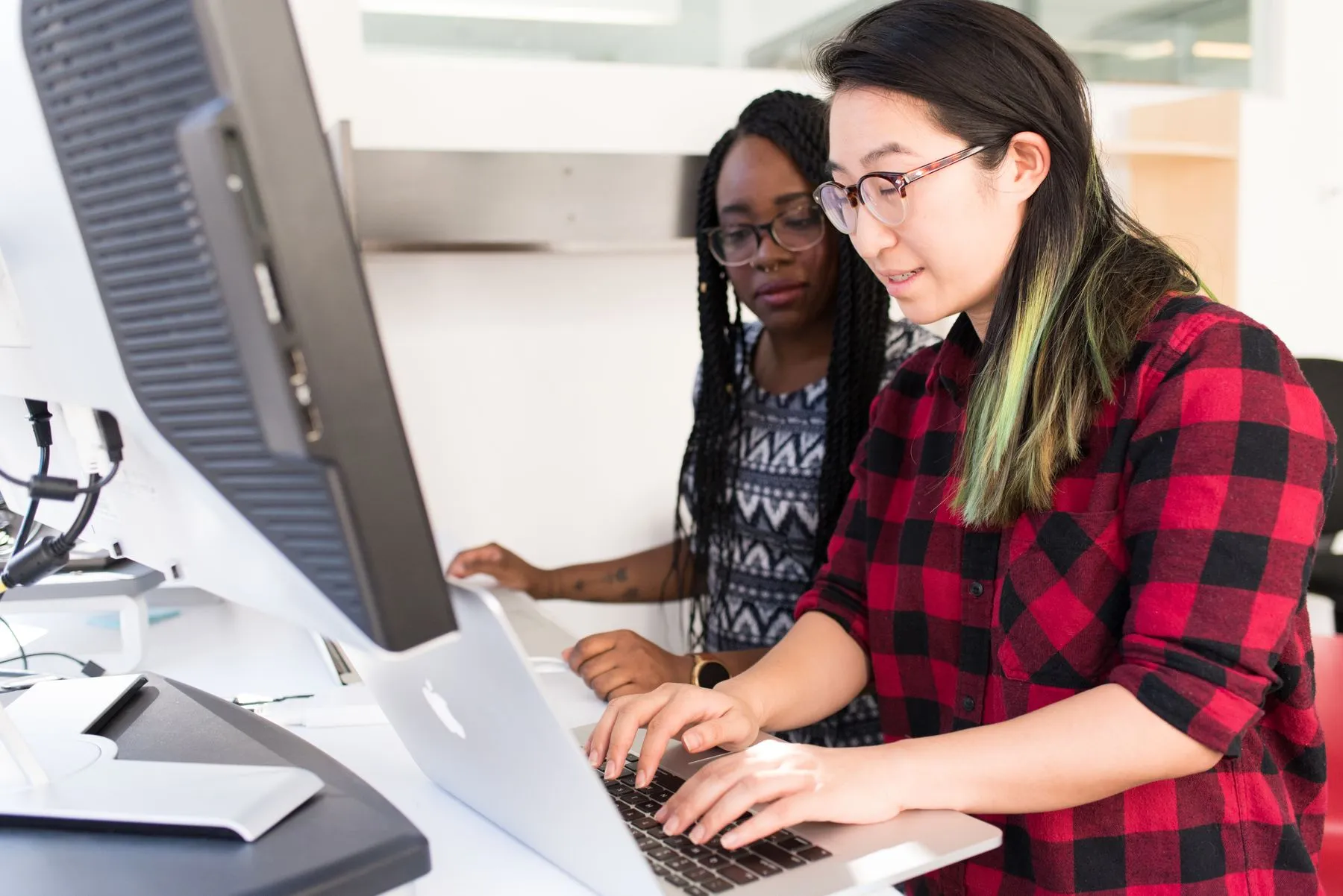 Two developers working through code together at a laptop.